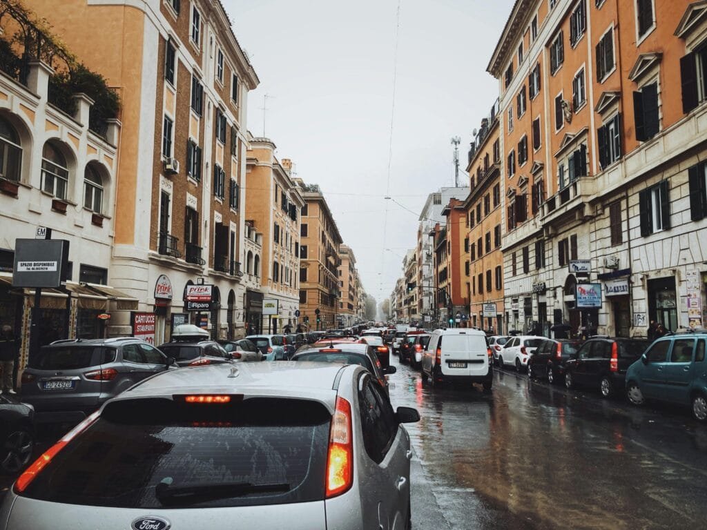 Will You Regret Not Traveling? How to Stop Making Excuses and Finally Go! Urban street scene with heavy traffic and historic architecture on a rainy day. Imposing the future possibility of travel regret.