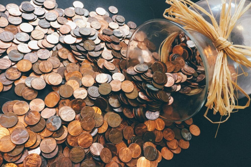 Will You Regret Not Traveling? How to Stop Making Excuses and Finally Go! Spilled jar of pennies creating a pattern of coins representing savings and finance.