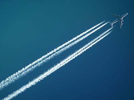Saving for Travel: How Today’s Sacrifices Create Tomorrow’s Freedom Aerial view of an airplane in flight, leaving vapor trails against a clear blue sky.