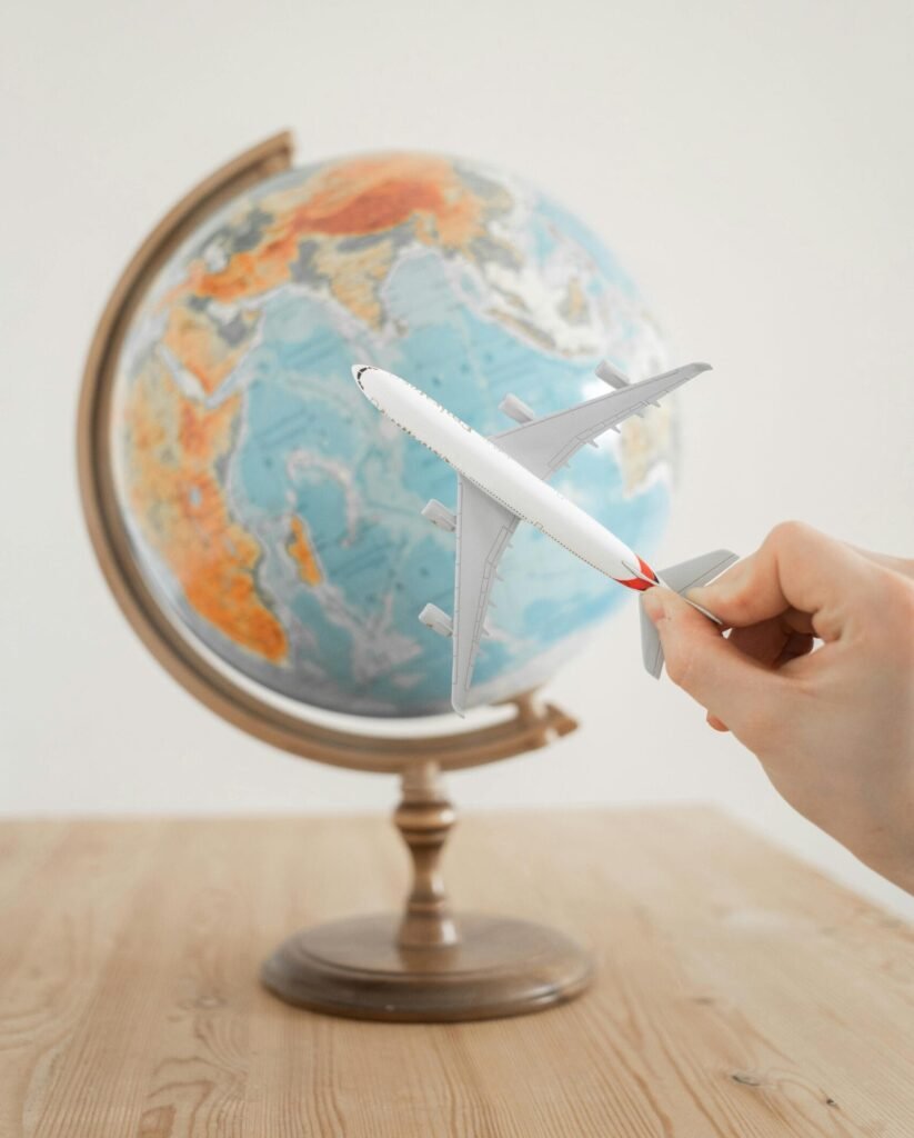 Booking Flights Wisely and Cheaply Close-up of a hand with a toy airplane in front of a globe, symbolizing travel and exploration and booking flights